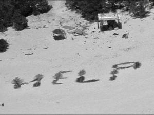 An einem Strand auf der Insel Pikelot ist die Botschaft «Help» mit Palmwedeln geschrieben. 