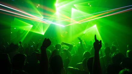 Eine Menschenmenge tanzt in einem Club vor einem DJ-Podest.