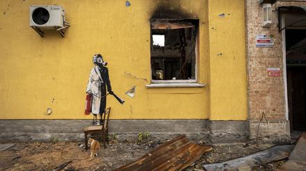 Auf der gelben Wand des Gebäudes ist ein Bild einer Person zu sehen, die eine Gasmaske und einen Feuerlöscher trägt. 