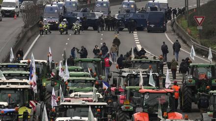 Landwirte und Traktoren stehen Militärfahrzeugen auf einer Autobahn gegenüber. 