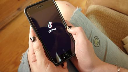 Ein Mädchen hält ein Handy mit der App von Tiktok in der Hand.