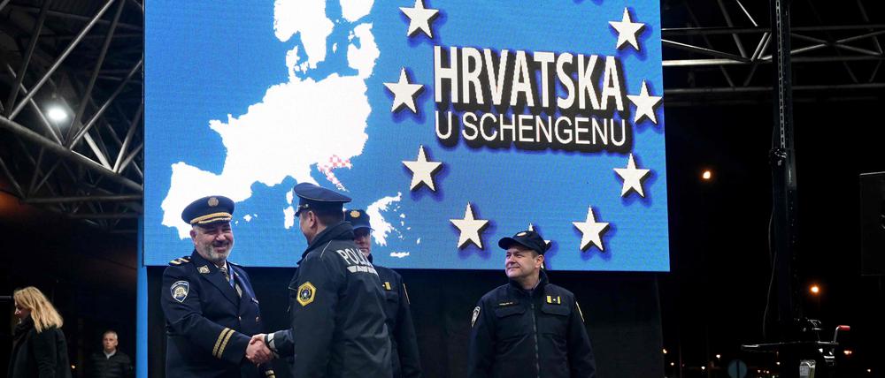 Grenzbeamte aus Slowenien und Kroatien schütteln sich am Übergang zwischen beiden Ländern in der Nacht zum 1. Januar die Hände. 