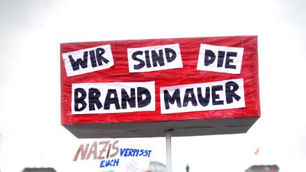 „Wir sind die Brandmauer“ steht auf dem Schild des Teilnehmers bei einer Demonstration gegen rechts in Berlin.