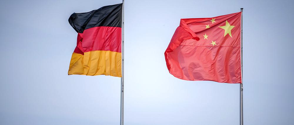 Die Flaggen von Deutschland und China wehen zum Auftakt des Deutschland-Besuchs der chinesischen Regierung im Wind vor dem Bundeskanzleramt, im Hintergrund die Kuppel des Reichstagsgebäudes.