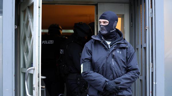 Einsatzkräfte der Polizei stehen bei einer Razzia im Eingangsbereich eines Gebäudes in Solingen (NRW).