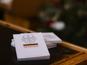 Vier Bücher mit dem Grundgesetz liegen während einer Einbürgerungsfeier auf einem Tisch im Ratssaal des Kieler Rathauses. 