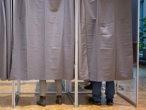 Zwei Wähler in Wahlkabinen.