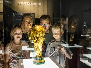 Eine Familie bewundert den deutschen Siegerpokal der Fußball-WM von 2014 in der Schatzkammer des Dortmunder Fußballmuseums.