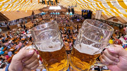  Besucher des Gäubodenvolksfestes stoßen in einem Festzelt mit Bierkrügen an. 