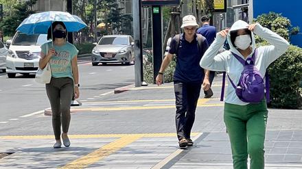 Menschen auf der Silom Road in Bangkok versuchen, sich vor der Hitze zu schützen. 