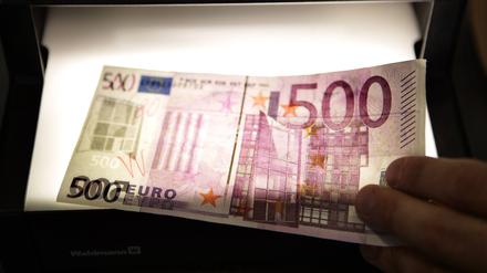 Ein gefälschter 500-Euro-Schein wird von einem Prüfgerät durchleuchtet (Symbolfoto).