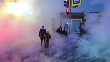 Menschen auf einer Straße in Novosibirsk (Russland), wo ein großer Heizkraftwerkausfall für Dampf auf der Straße sorgt.