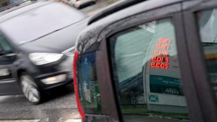 Kraftstoffpreise einer Tankstelle spiegeln sich in der Scheibe eines Autos.