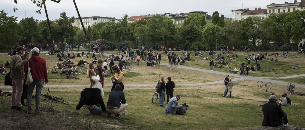  Menschen sitzen am 1. Mai 2020 in kleinen Gruppen auf einer Wiese im Görlitzer Park in Berlin Kreuzberg. Aufgrund der Corona Pandemie sind alle Demonstrationen und Großveranstaltungen zum 1. Mai abgesagt. Foto: bildgehege Automat für Schutzmasken