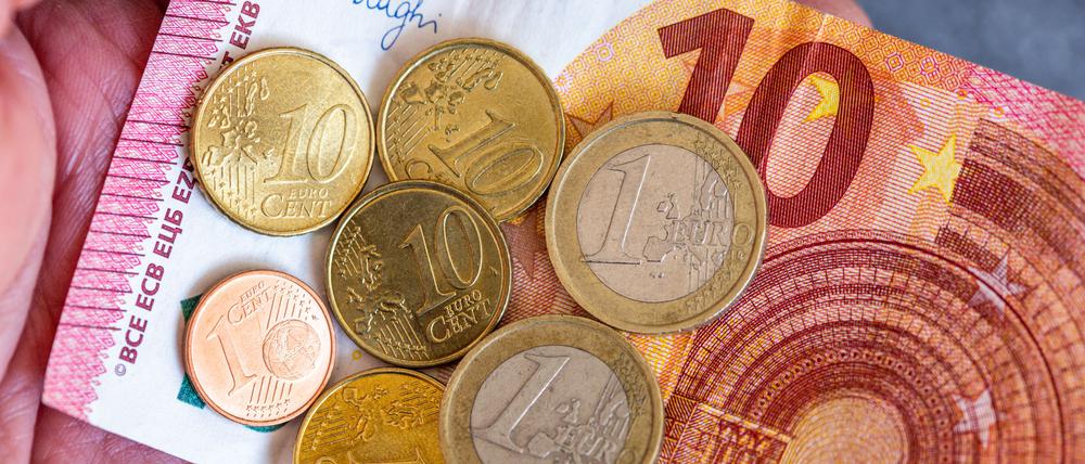 Geldscheine und Euromünzen mit dem Wert von 12,41 Euro liegen auf einer Hand – der derzeitige Mindestlohn in Deutschland.