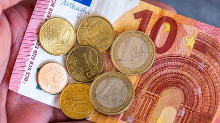 Geldscheine und Euromünzen mit dem Wert von 12,41 Euro liegen auf einer Hand.