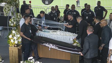 Beerdigungshelfer decken den Sarg des verstorbenen brasilianischen Fußballstars Pele auf. 