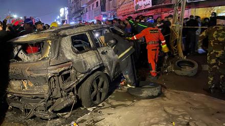 Mitglieder der Zivilverteidigung versammeln sich an einem verbrannten Fahrzeug, das von einem US-Drohnenangriff im Osten Bagdads getroffen wurde. 