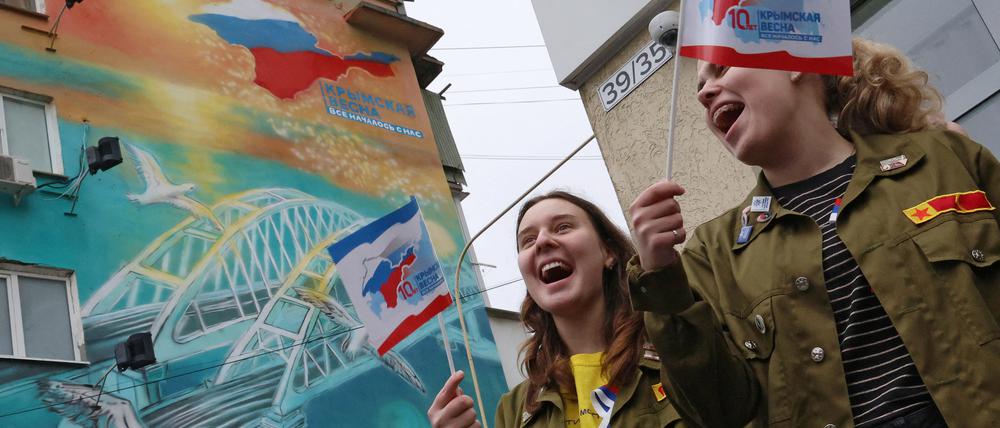 Zwei Frauen schwenken Fähnchen für die Annexion der Krim vor zehn Jahren in der Innenstadt von Simferopol.