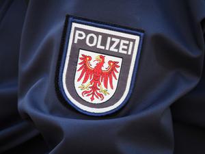 Das Logo der Brandenburger Polizei mit rotem Adler und Schriftzug auf dem Ärmel der Jacke einer Polizeibeamtin (Symbolfoto).