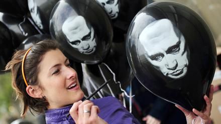 Anna Büchling zersticht am Donnerstag (26.04.2012) vor der russischen Botschaft in Berlin einen Luftballon mit dem Bild von Putin. In den Ballons befinden sich Zettel mit einer Petition an Wladimir Putin, mit der Aufforderung eine freie Berichterstattung in seinem Land zuzulassen. Foto: Hannibal dpa/lbn ++ +++ dpa-Bildfunk +++