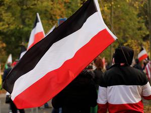 Ein Teilnehmer mit einer schwarz-weiß-roten Reichsflagge während einer Demonstration von Reichsbürgern und anderen Rechtsextremen.