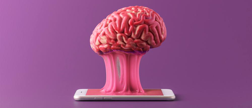 The human brain is stuck to a smartphone on a purple background. Concept of a day without gadgets.