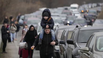 Flüchtlinge gehen an Fahrzeugen vorüber, die vor dem Grenzübergang von der Ukraine nach Moldawien warten.