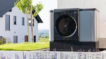 Eine Wärmepumpe steht in einem Garten eines Einfamilienhauses in einem Neubaugebiet.