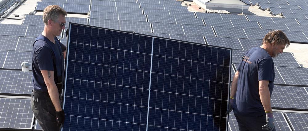 Mitarbeiter der Leipziger Solargesellschaft mbH tragen ein Solarmodul auf dem Dach der Frische GmbH Köhra.
