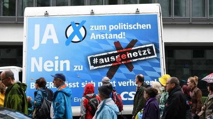 Teilnehmer der Demonstration "#ausgehetzt - Gemeinsam gegen die Politik der Angst" vor einem CSU-Plakat in München.