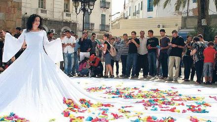 Bunte Wünsche. Raeda Saadeh, Palästinenserin, zeigt ihre Performance "The Wishes Tree am Eingang der Medina von Tunis. Begeistert schrieben die Tunesier ihre geheimsten Wünsche auf Stofffetzen und warfen sie auf das Kleid.