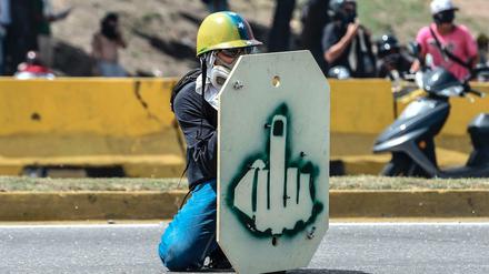 Ein Demonstrant in Caracas schützt sich hinter einem selbstgebauten Schild. 