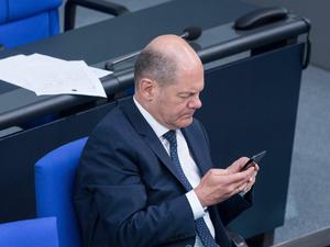 Olaf Scholz mit Blick auf sein Handy im Bundestag (Archivbild) 