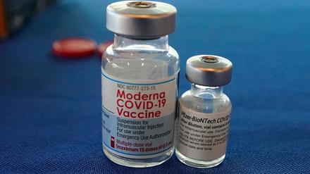 Leere Behälter der COVID-19-Impfstoffe von Pfizer/Biontech und Moderna stehen auf einem Tisch.
