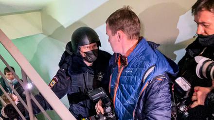 Ein Polizist steht vor Fotografen von einer Tür der Wohnung von Navalnys Bruder.