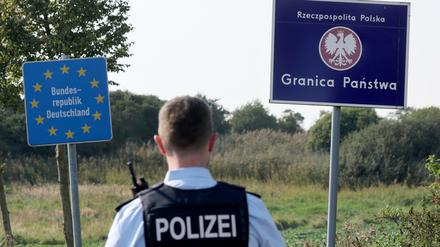 Bei einer flexiblen Schwerpunktkontrolle an der deutsch-polnischen Grenze steht ein Bundespolizist vor den Schildern für Deutschland und Polen. 