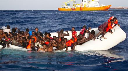 Flüchtlinge sitzen auf dem Mittelmeer in einem sinkenden Schlauchboot.