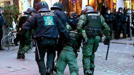 Polizisten tragen einen verletzten Kollegen bei Ausschreitungen im Hamburger Schanzenviertel.