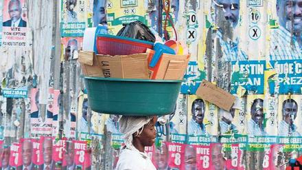 Reste einer missglückten Wahl. Eine Frau läuft an einer Wand mit Plakaten in der Hauptstadt Port-au-Prince vorbei. Foto: Reuters