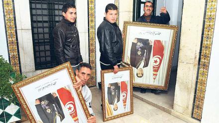 Ein Land steht kopf. Angestellte im Amt des tunesischen Premierministers entfernen Porträts von Ex-Staatschef Ben Ali.