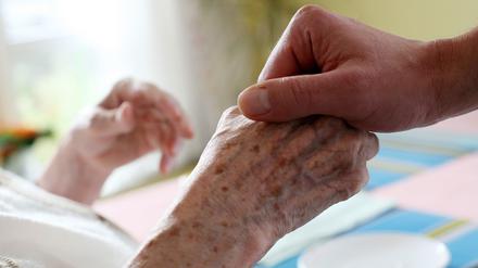 Ein Pfleger hält die Hand einer Frau.