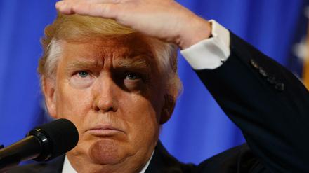 Donald Trump schirmt seine Augen mit der Hand ab, um trotz der blendenden Scheinwerfer sehen zu können. 