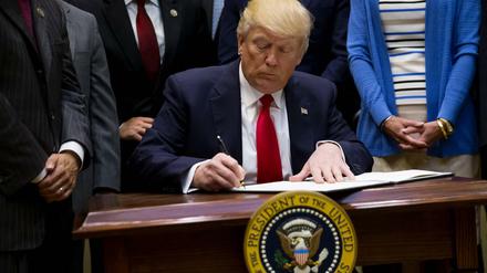 Unterschriften, die bis nach Deutschland wirken. US-Präsident Trump bei der Arbeit. 