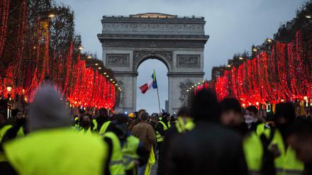 Frankreich, Paris: Demonstranten stehen vor dem Arc de Triomphe. Bei den Demonstrationen der «Gelben Westen» in Paris . Die Polizei setzte Tränengas und Wasserwerfer ein.