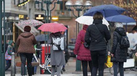 Passanten in Hamburg schützen sich auf dem Rathausmarkt mit Regenschirmen vor dem Dauerregen.