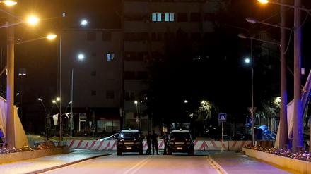 Kosovo, Mitrovica: Polizisten sichern mit ihren Fahrzeugen eine Brücke, während in der Stadt Sirenenalarm zu hören ist.