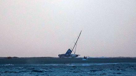Landgang. Die Rennyacht Vestas Wind liegt auf die Seite geworfen auf einer Sandbank im Indischen Ozean. 