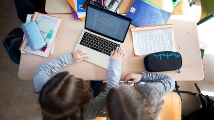 Zwei Schülerinnen arbeiten im Klassenraum gemeinsam an einem Laptop.
