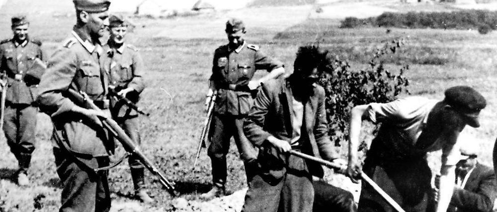 Erzwungen. Wehrmachtssoldaten eines Exekutionskommandos lassen sowjetische Partisanen im Zweiten Weltkrieg ihr eigenes Grab ausheben. An den Massenverbrechen des NS-Regimes in der Sowjetunion waren auch einige Verschwörer des 20. Juli beteiligt. 